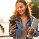 student-holding-laptop-and-using-smartphone